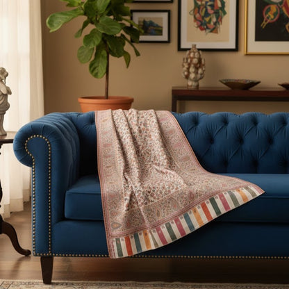 Blue sofa with a patterned blanket draped over it in a living room setting.