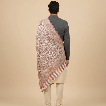 Person wearing a patterned shawl over a traditional outfit on a beige background