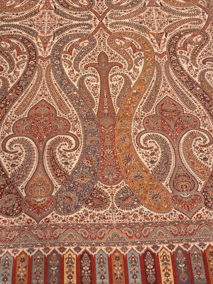 Decorative shawl with intricate patterns on a light wooden floor.