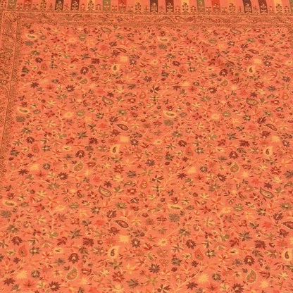 Decorative folded pink pure wool shawl with intricate patterns on a light wooden floor.