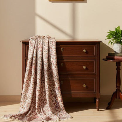 Wooden dresser with floral pure wool shawl in kani design, framed pictures on the wall, and a small plant.