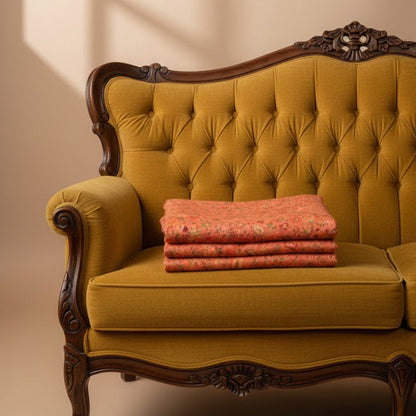 Yellow velvet sofa with wooden frame and decorative elements, featuring a folded pink pure wool shawl on a beige background.