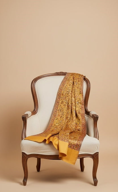 Yellow patterned stole draped over a wooden armchair with a beige background