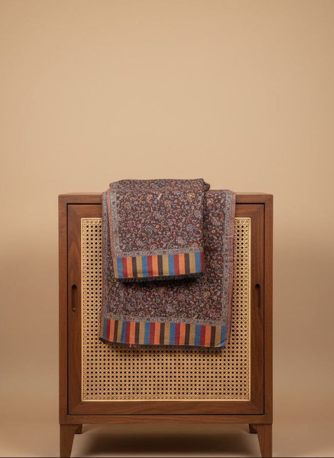 Silk wool patterned jamawar kani shawl with intricate designs with colorful stripes on a wooden cabinet against a beige background