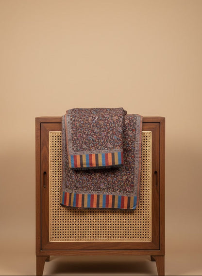 Silk wool patterned jamawar kani shawl with intricate designs with colorful stripes on a wooden cabinet against a beige background