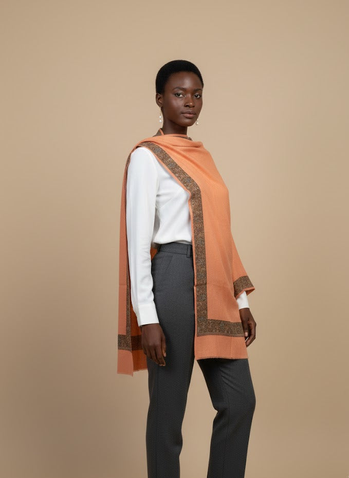 Person wearing peach pashmina shawl  with a pattern on a beige background