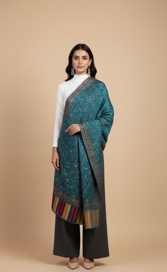 Woman wearing an azure blue faux Pashmina patterned stole over a white top on a beige background