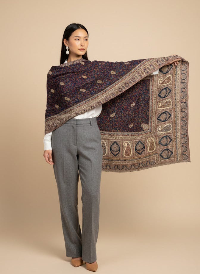 Woman holding a patterned kalamkari hand embroidered shawl against a beige background