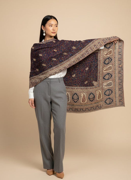 Woman holding a patterned kalamkari hand embroidered shawl against a beige background