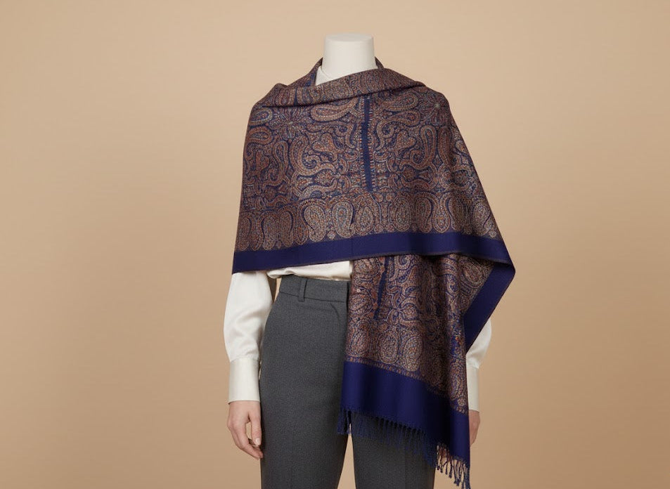 Mannequin wearing a patterned silk wool blend, large patterned jamawar kani shawl with intricate paisley pattern on a beige background