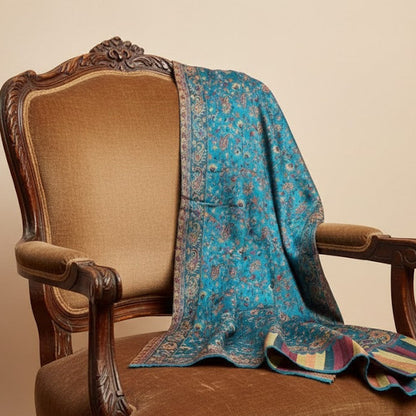 Decorative azure blue faux Pashmina stole draped over a brown armchair with a beige background