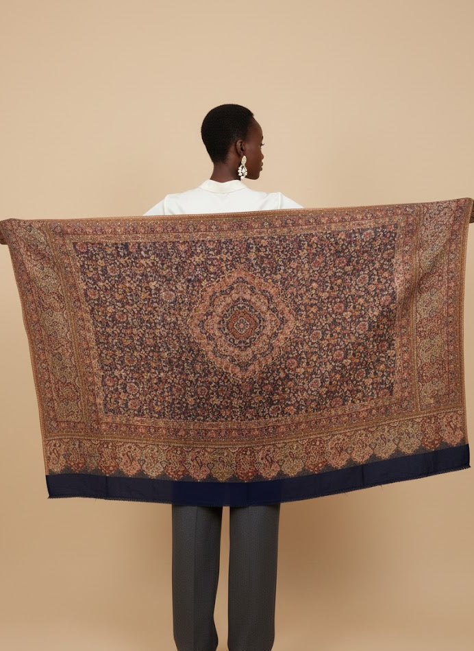 Person holding a large patterned deep indigo blue hand woven pure wool patterned jamawar kani shawl  against a beige background
