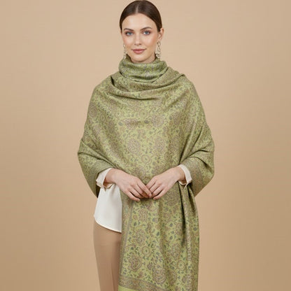 Woman wearing a sage green paisley patterned faux pashmina silk blend  on a beige background