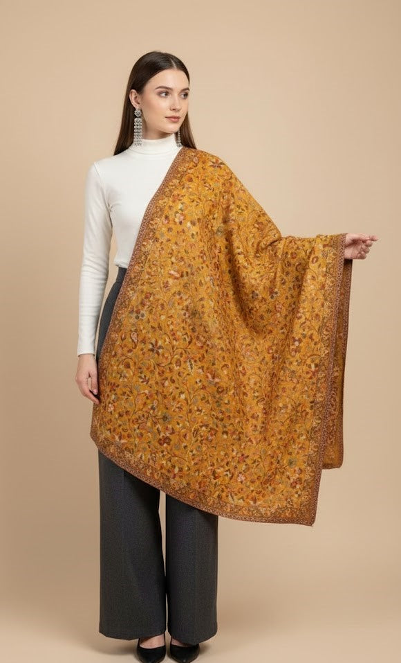 Woman wearing a large mustard-colored floral shawl against a beige background