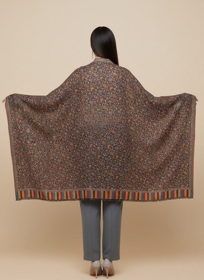 Person wearing a patterned shawl over their shoulders on a beige background