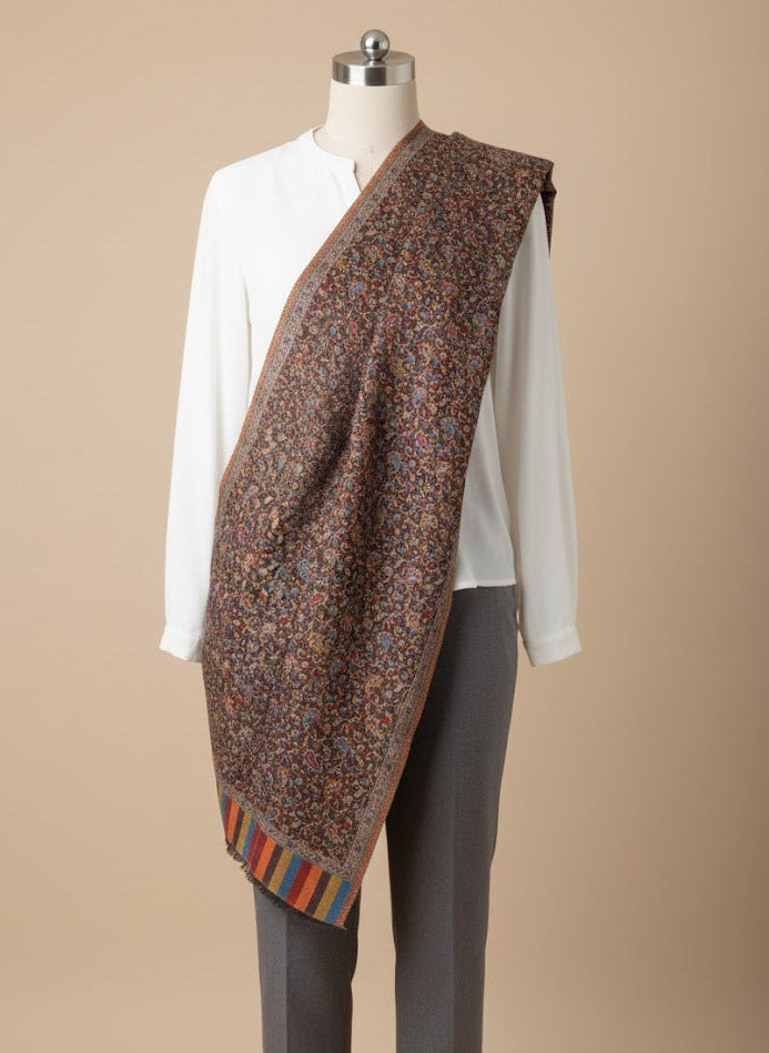 Mannequin wearing a patterned shawl over a white shirt and gray pants on a beige background