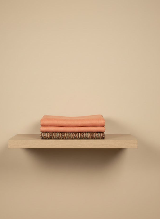Beige shelf with folded towels on a beige wall