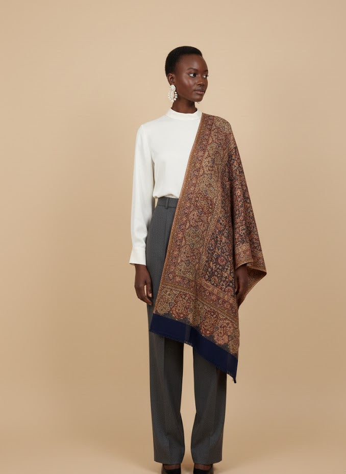 Woman wearing a patterned deep indigo blue hand woven pure wool patterned jamawar kani shawl  on a beige background