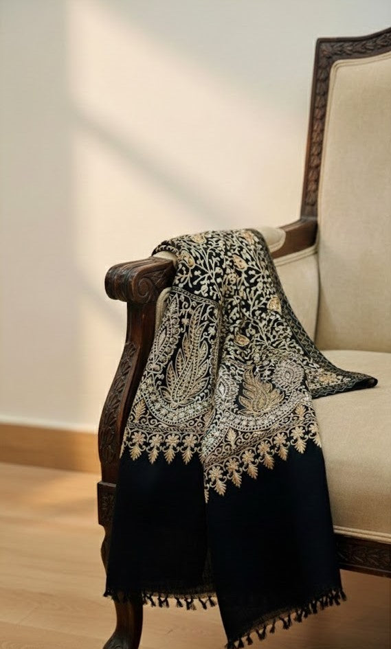 Black and white patterned pashmina shawl draped over a wooden armchair with a beige cushion.