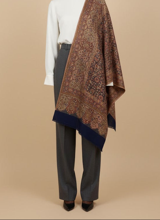 Person wearing a patterned shawl over a white shirt and gray pants on a beige background