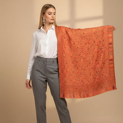 Woman holding a folded pink pure wool shawl patterned against a beige background