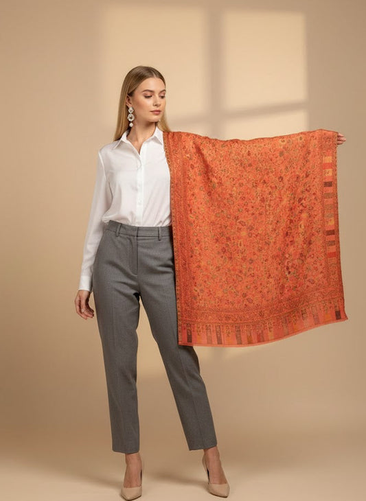 Woman holding a folded pink pure wool shawl patterned against a beige background