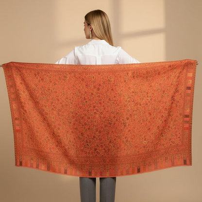 Person holding a large pink patterned shawl against a beige background