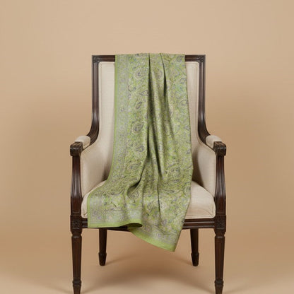Sage green paisley patterned faux pashmina silk blend  draped over a white chair against a beige background