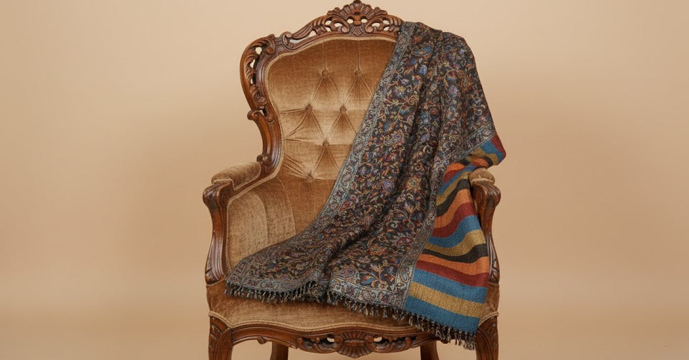 Decorative silk wool patterned jamawar kani shawl with intricate designs draped over an ornate chair against a beige background