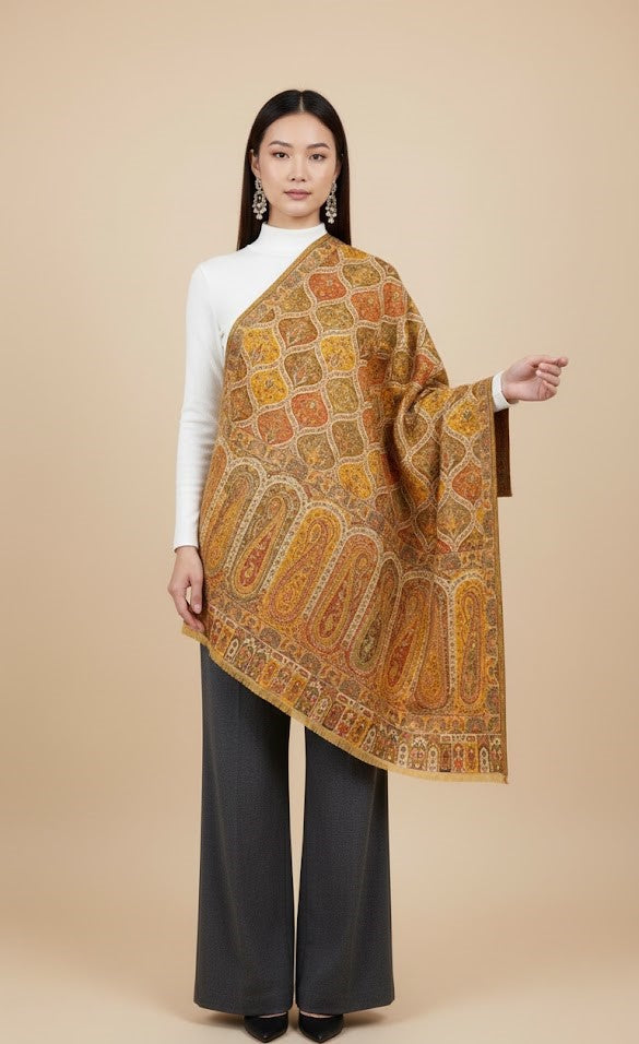 Woman wearing a patterned Yellow patterned kalamakari kani double beam stole in pure wool over a white top and dark pants on a beige background