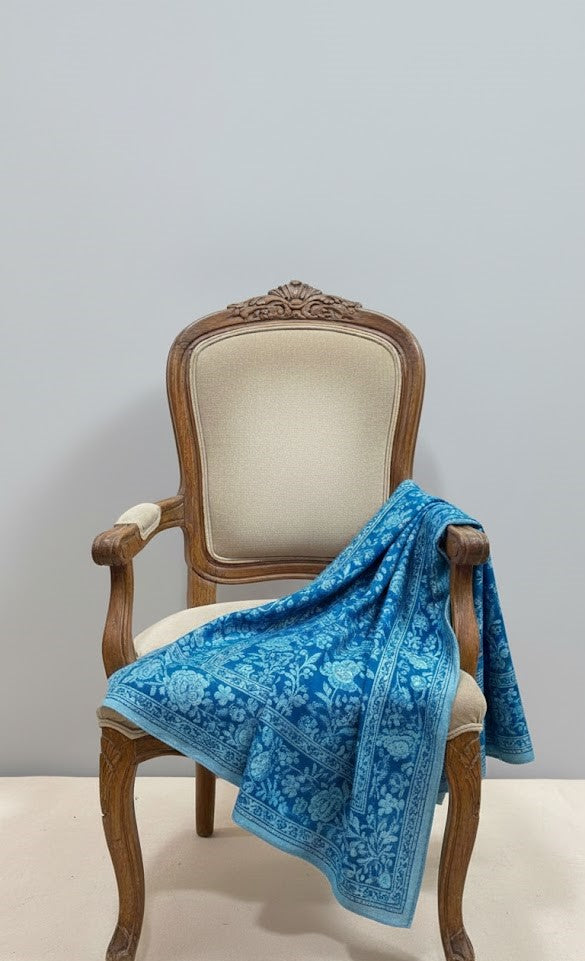 Blue floral-patterned pashmina shawl draped over a wooden chair with a gray background